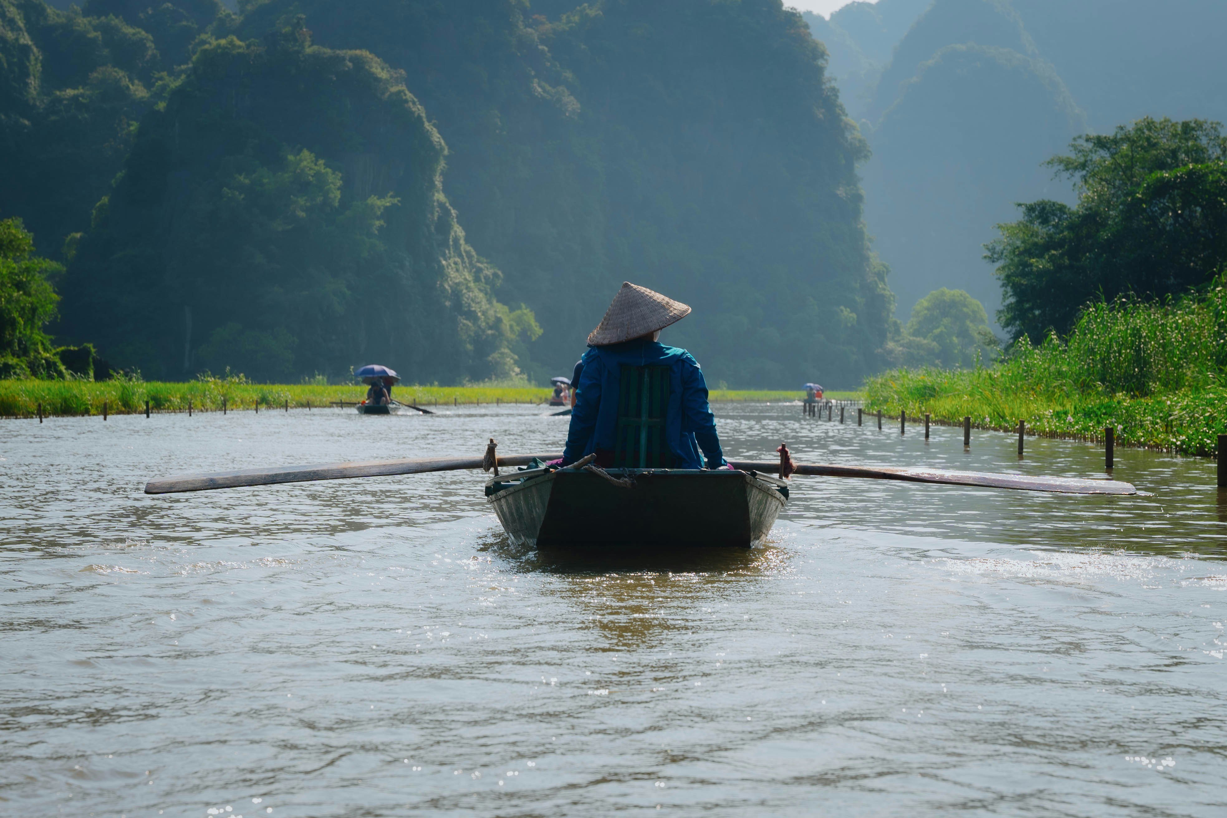 a person sitting in a boat on a river Ninh Bình (Bái Đính – Tràng An)