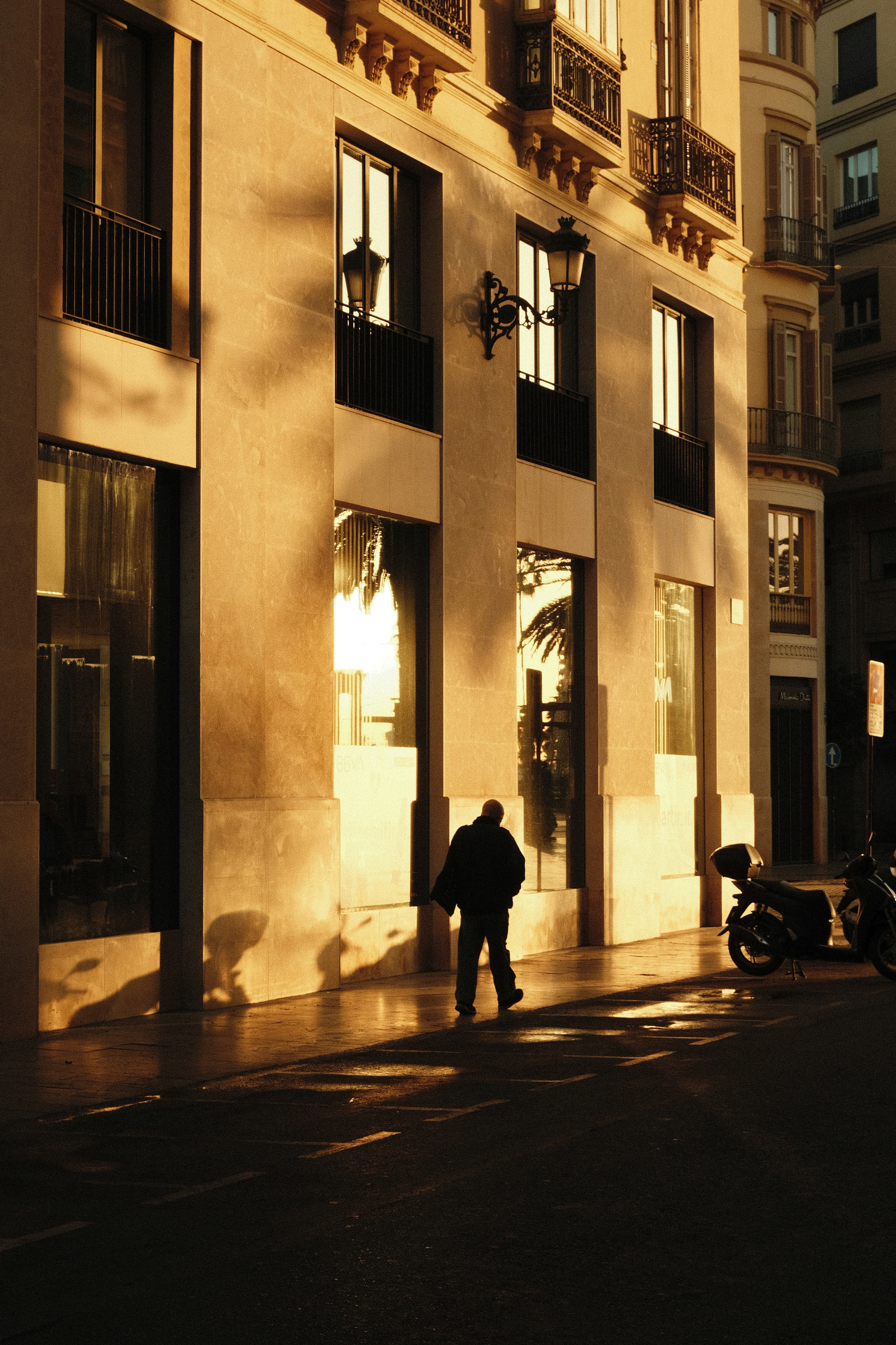 a man walking down a street next to a tall building