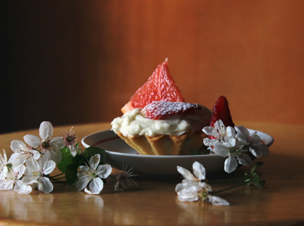 a cupcake topped with whipped cream and strawberries on a plate