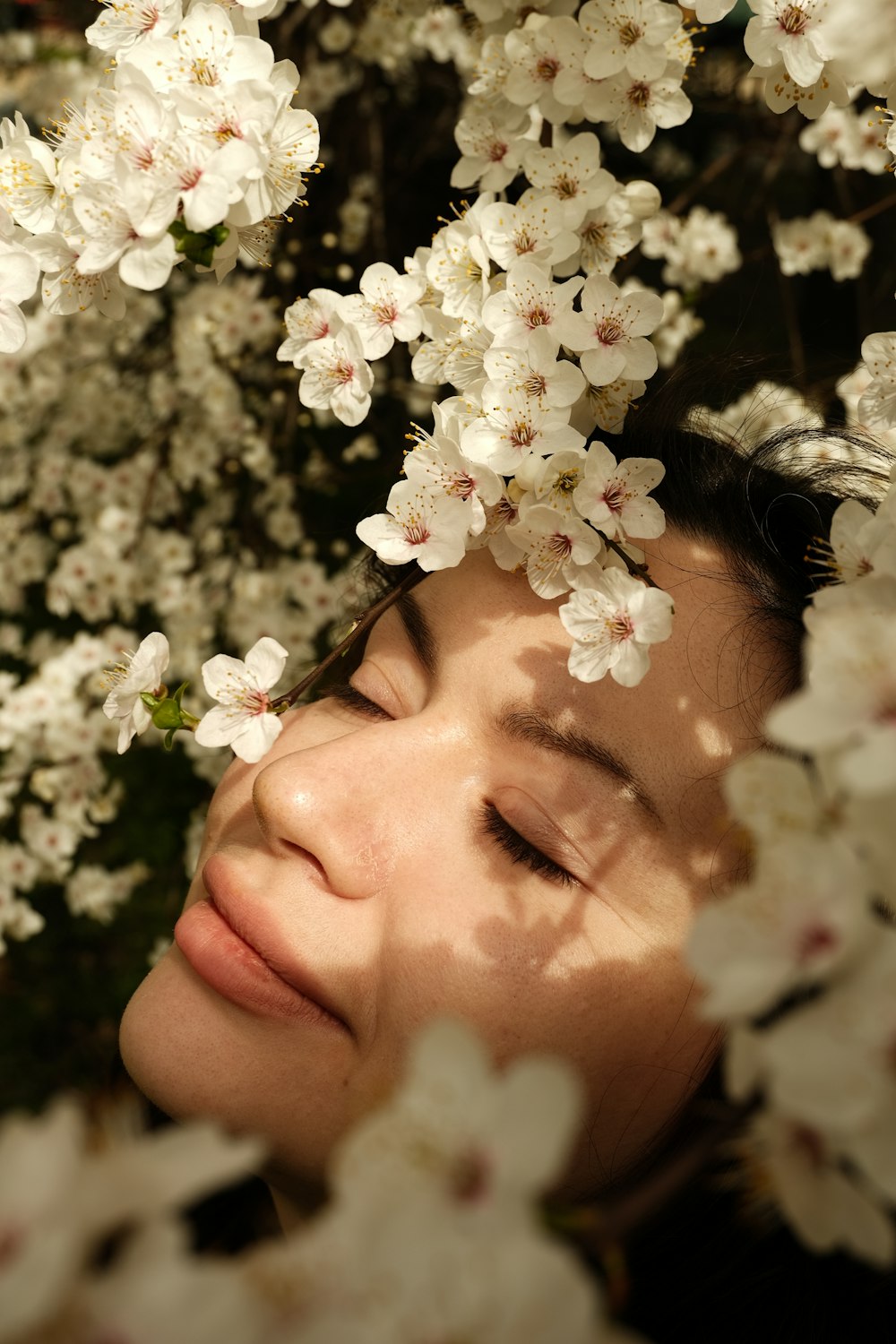 a woman with her eyes closed is surrounded by white flowers