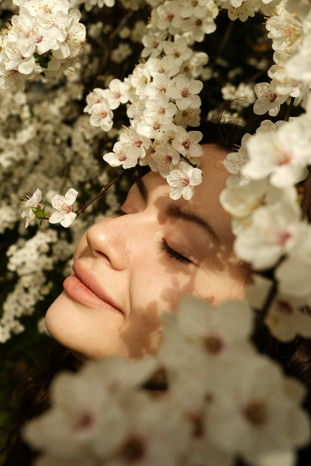 a woman with her eyes closed is surrounded by white flowers