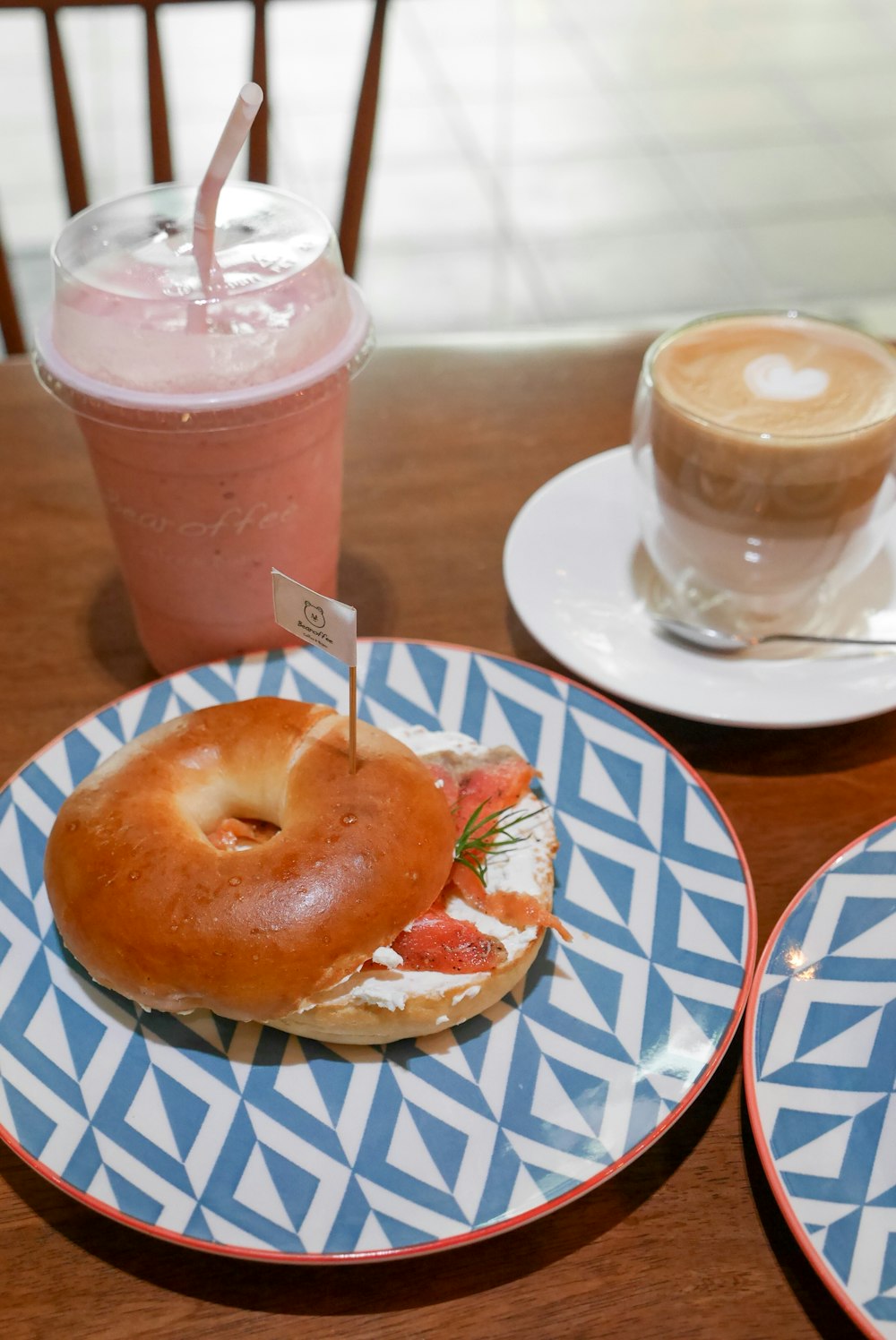 two plates with a bagel and a drink on a table