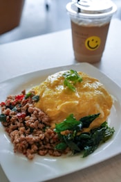 a white plate topped with food next to a cup of coffee