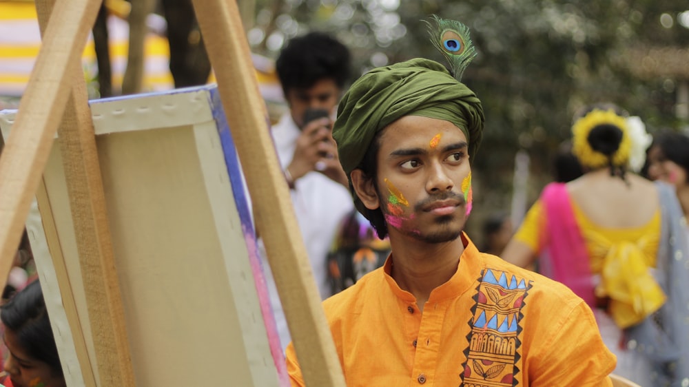 a man with a green turban standing in front of a painting easel