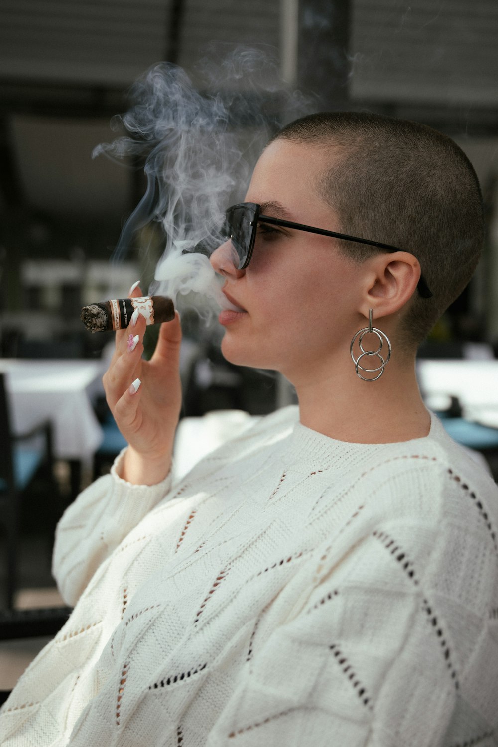 a woman smoking a cigarette in a white sweater