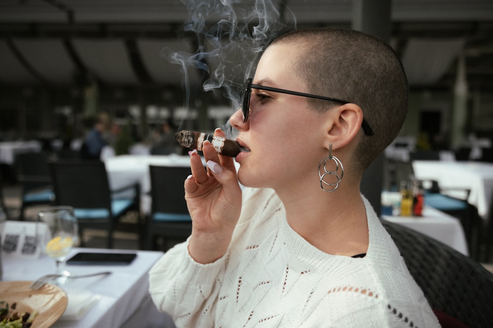 a woman sitting at a table smoking a cigarette