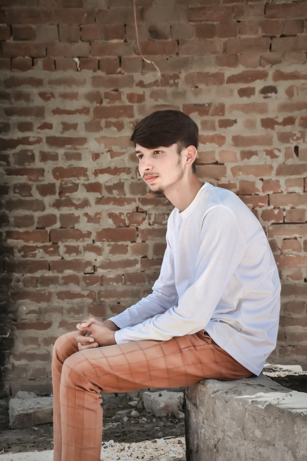 a young man sitting on top of a cement block