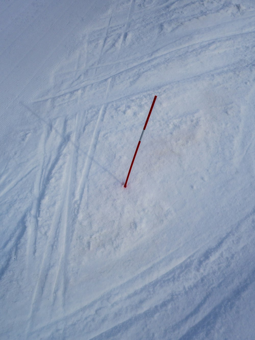 a ski slope with a red pole sticking out of the snow