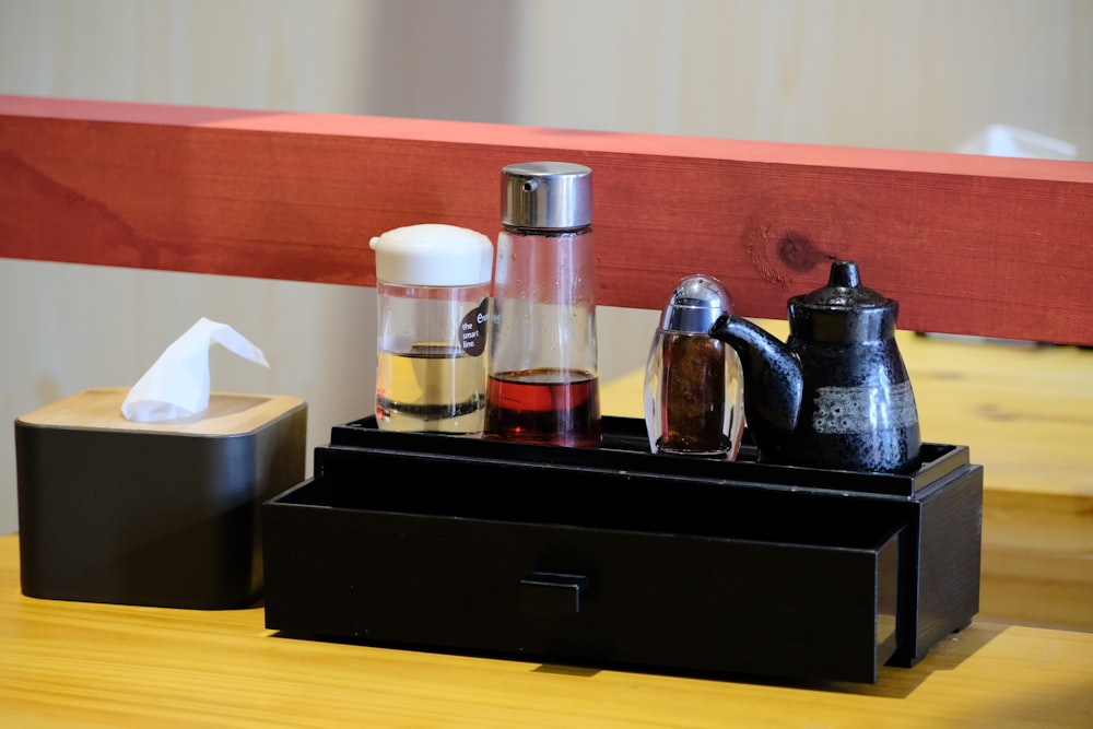 a wooden table topped with a black tray filled with different types of items
