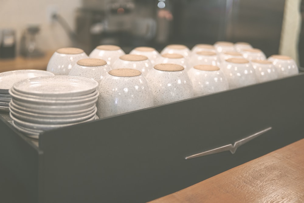 a stack of white plates sitting on top of a wooden table