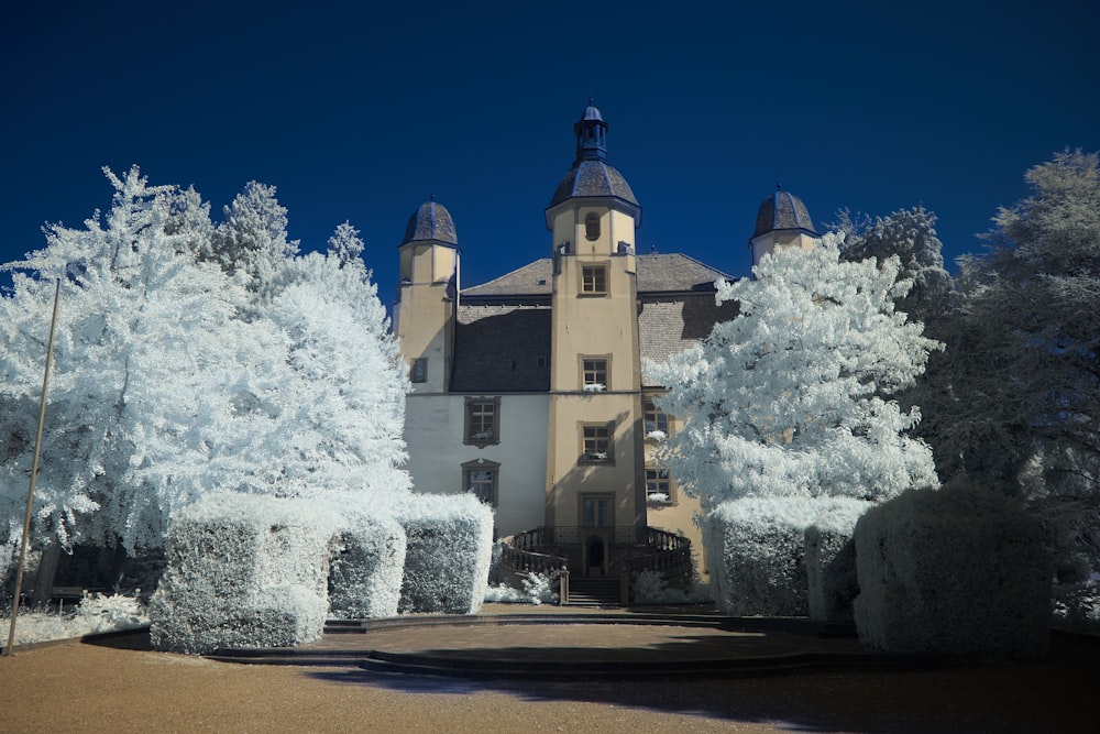 un grand bâtiment blanc entouré d’arbres et de buissons