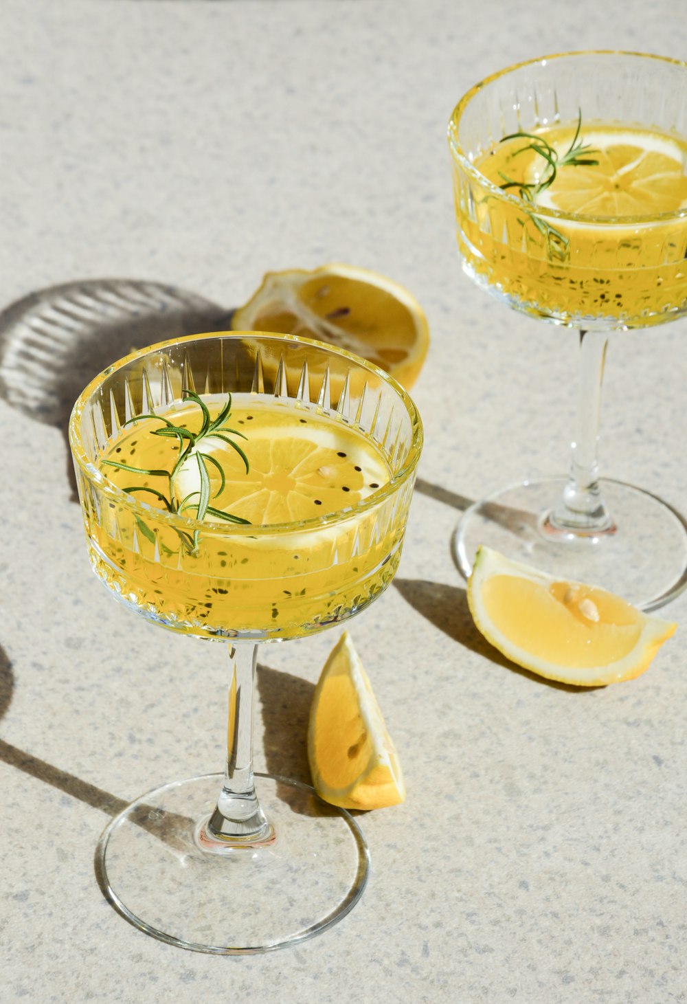 a couple of glasses filled with liquid next to a slice of lemon