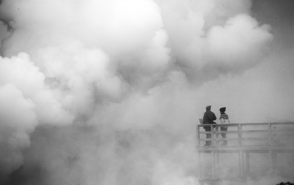 a black and white photo of two people on a bridge