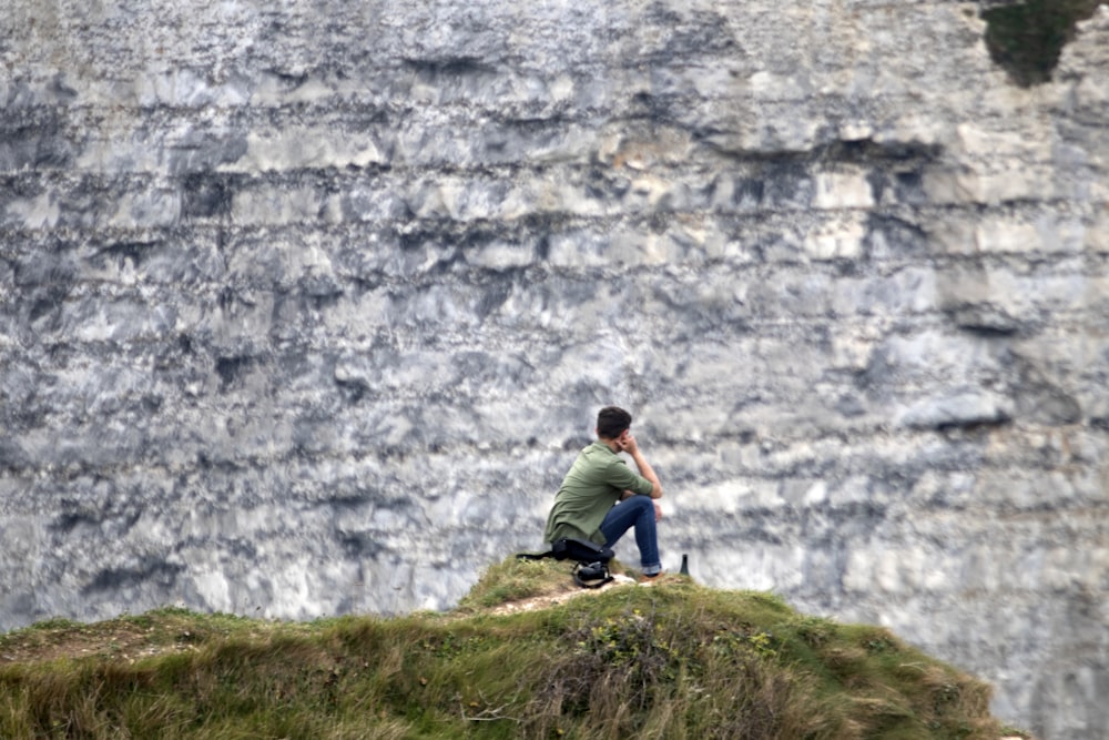 a man sitting on top of a lush green hillside