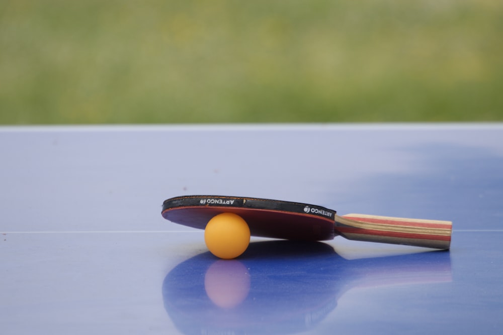 una paleta de ping pong y una pelota de ping pong sobre una mesa