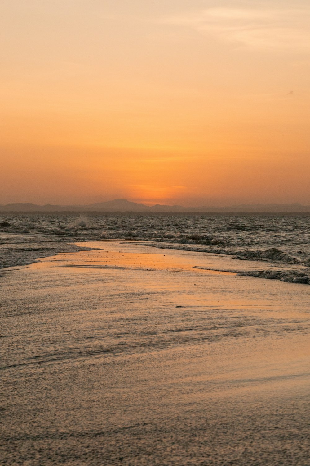 o sol está se pondo sobre a água na praia