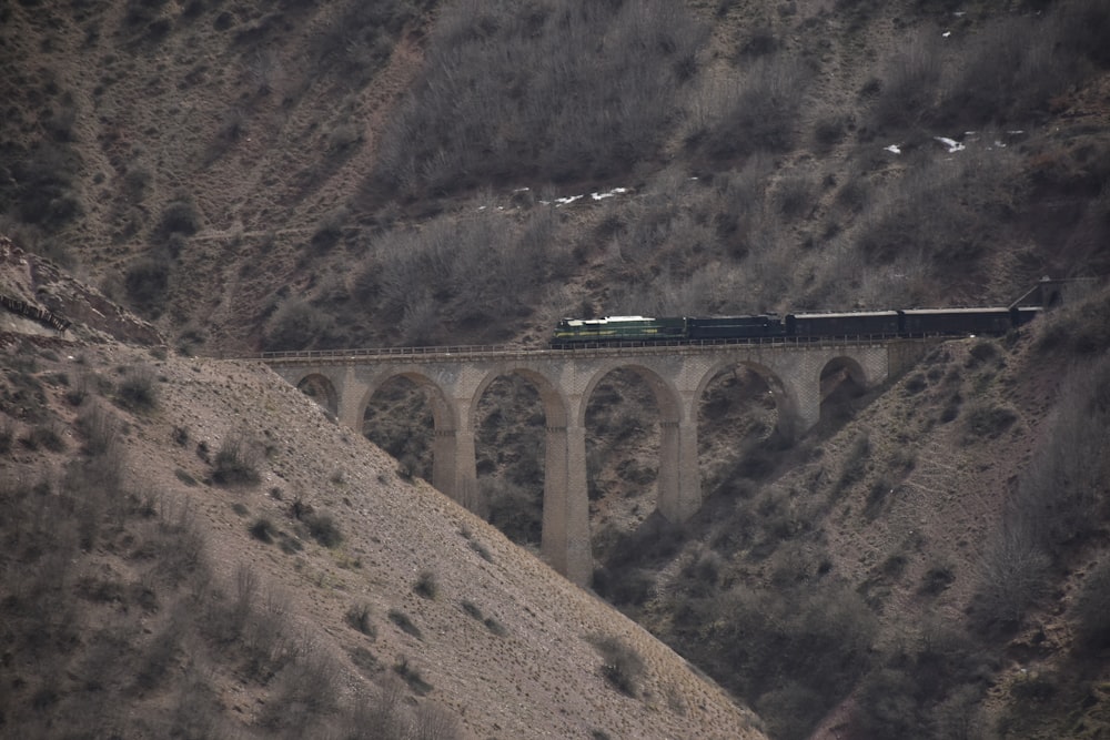 a train traveling over a bridge in the mountains