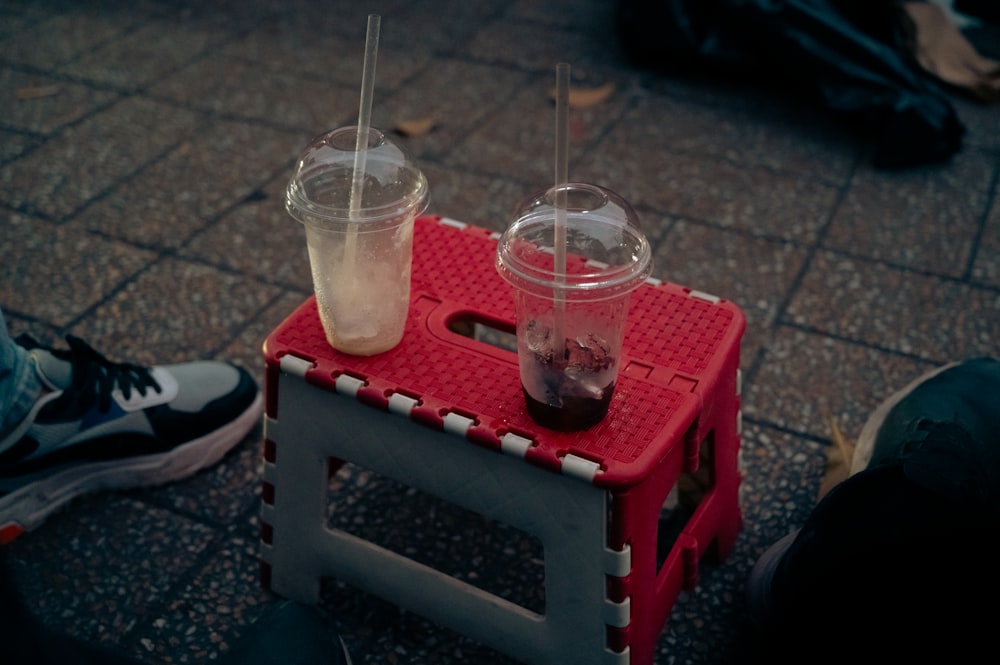 two plastic cups sitting on top of a red stool