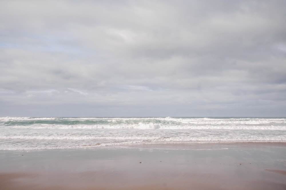 a sandy beach with waves coming in to shore