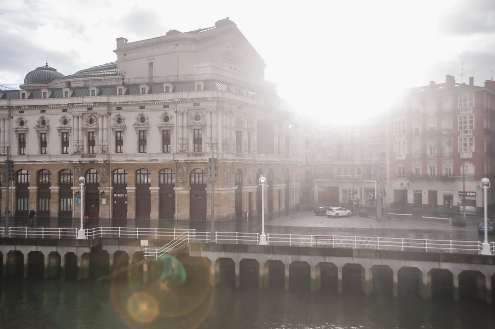 the sun shines brightly on a building next to a body of water