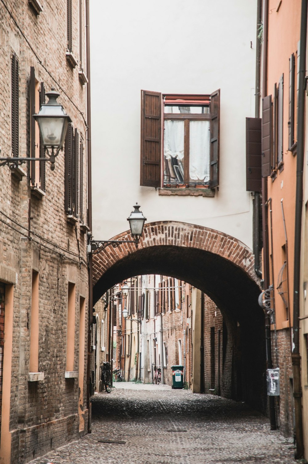 a narrow alleyway with a brick arch leading to a window