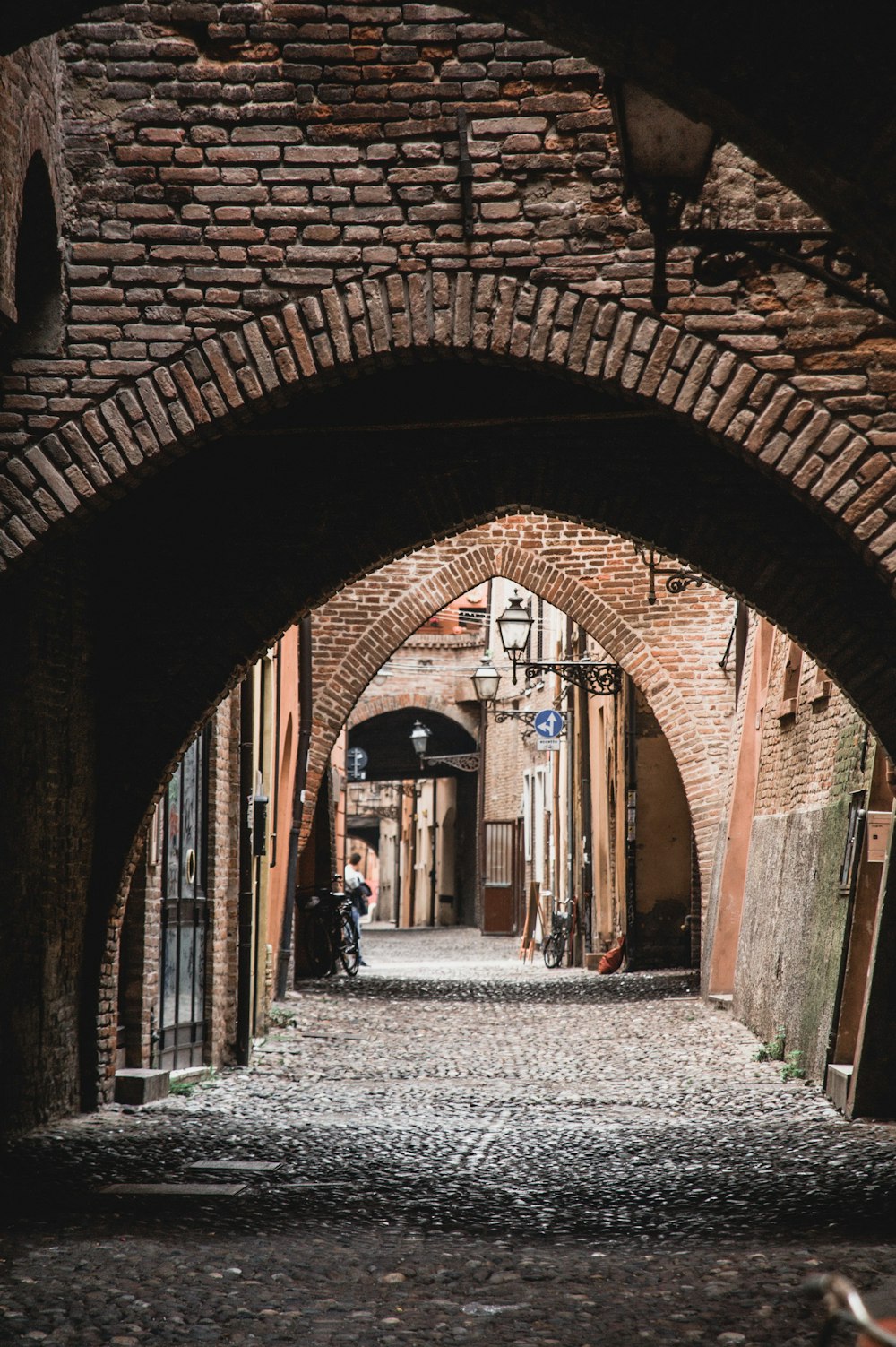 a narrow alley way with a person sitting on a bench
