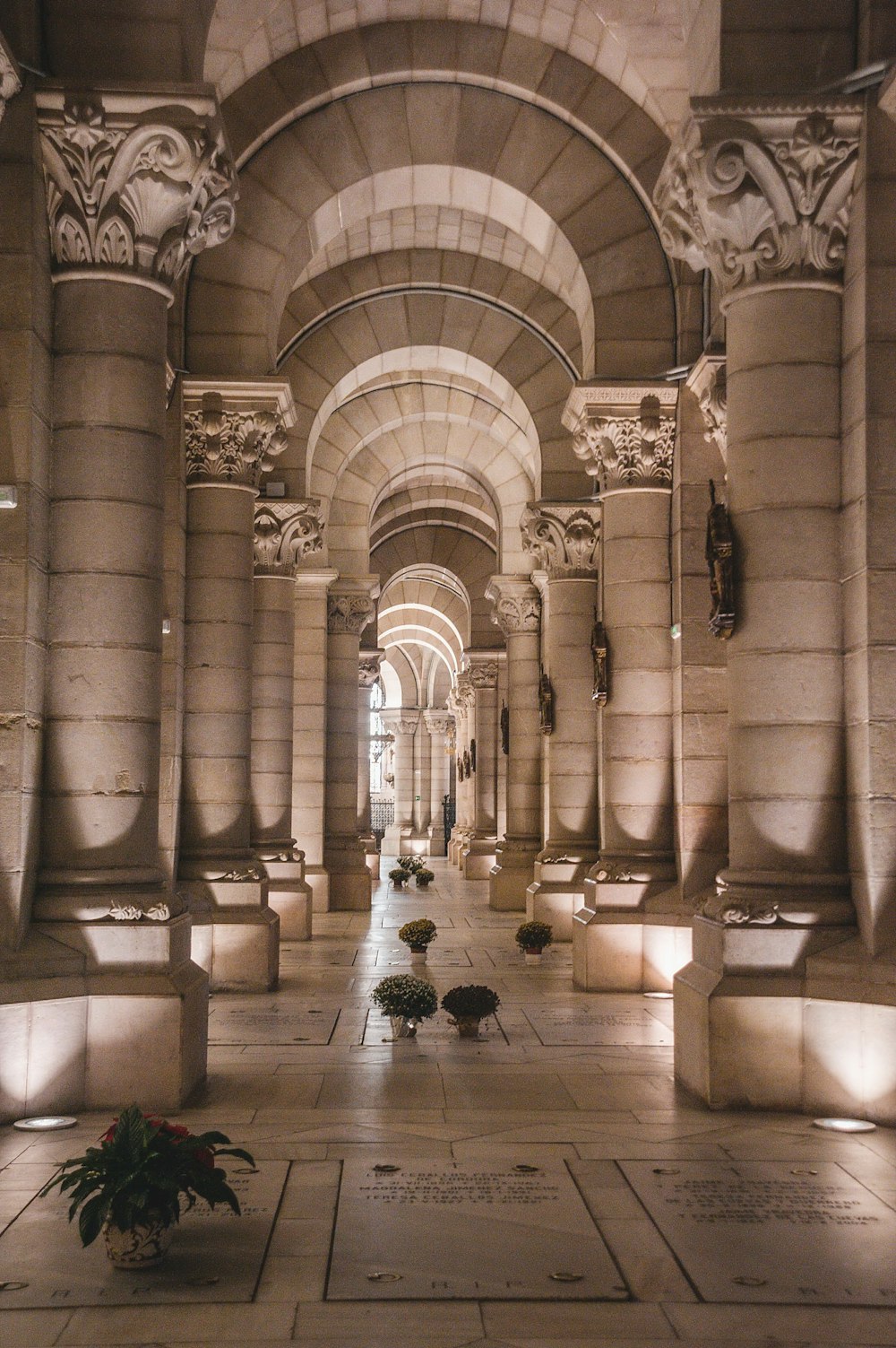a long hallway with columns and flowers on the floor