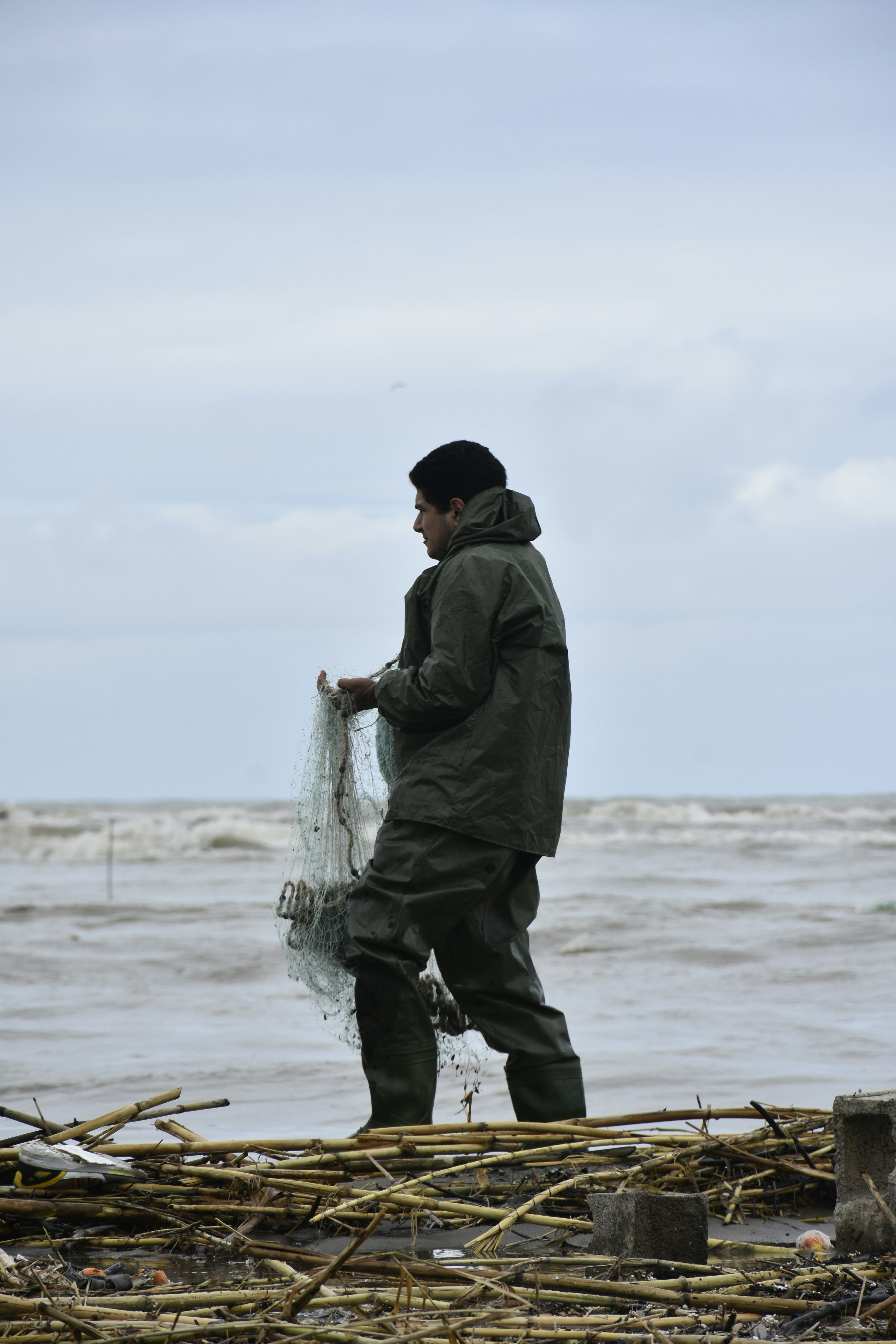 un uomo in piedi su una spiaggia con in mano una rete da pesca