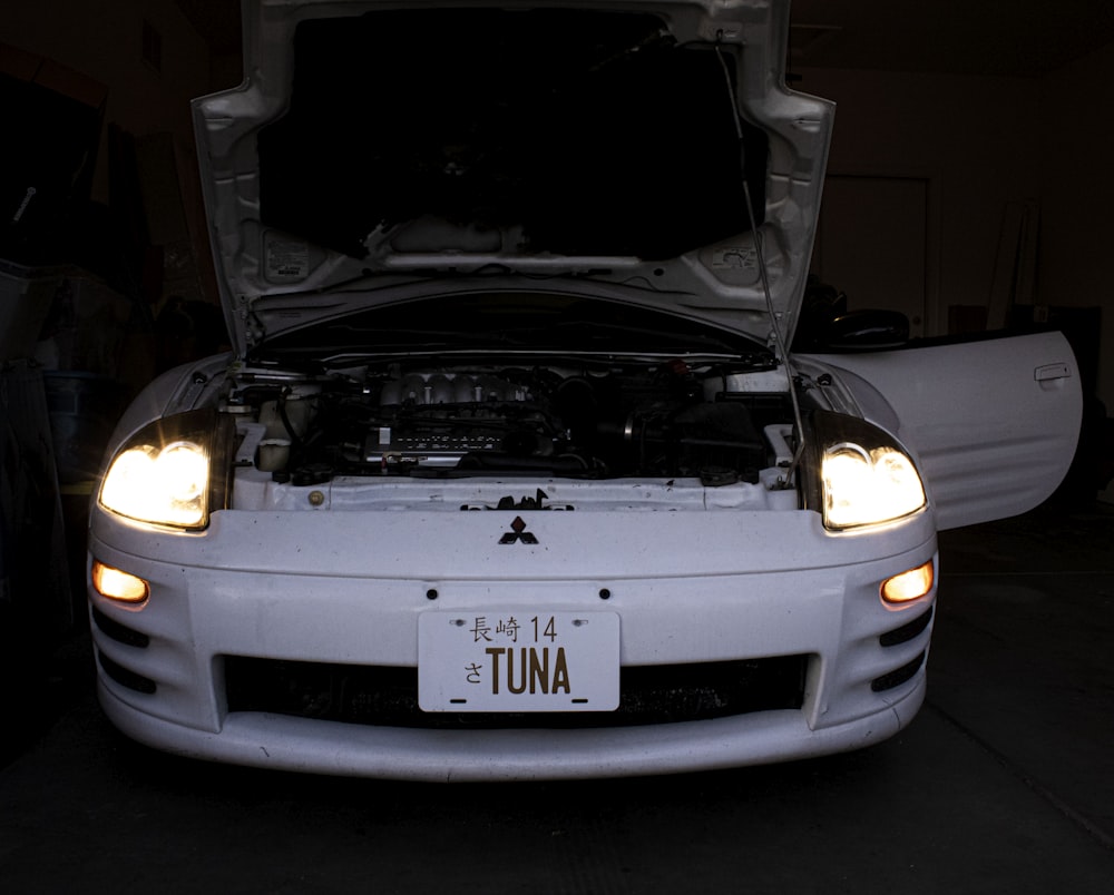 a white car with its hood open in a garage