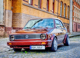 a red car parked on a cobblestone street