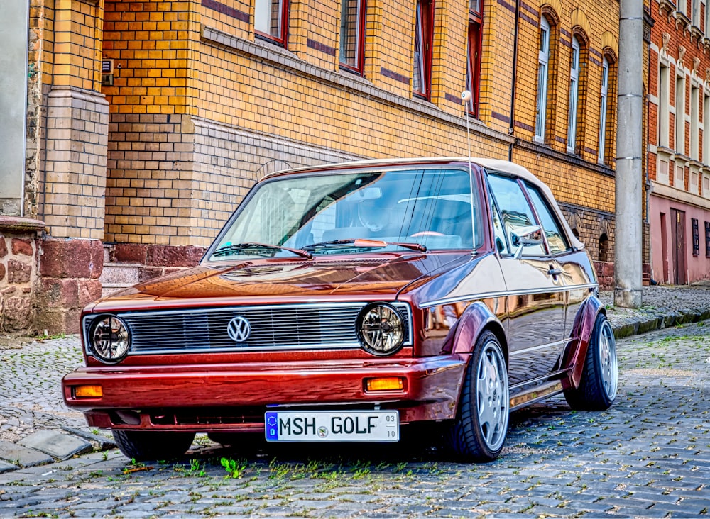 a red car parked on a cobblestone street