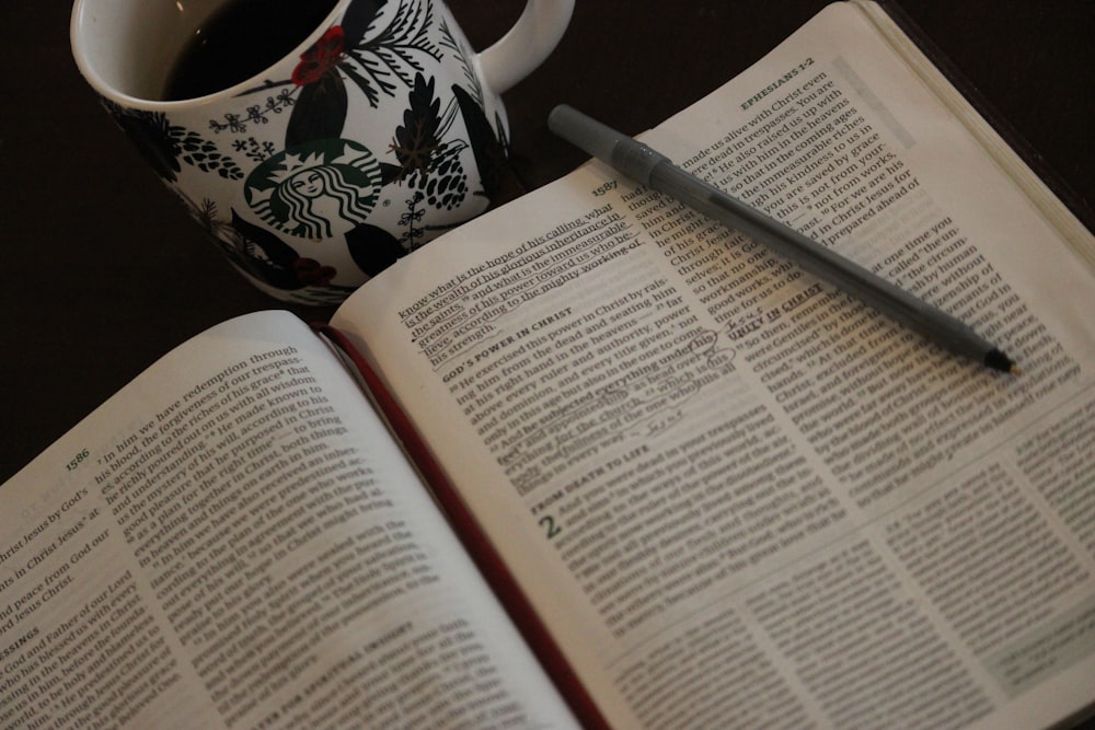 uma xícara de café e um livro sobre uma mesa