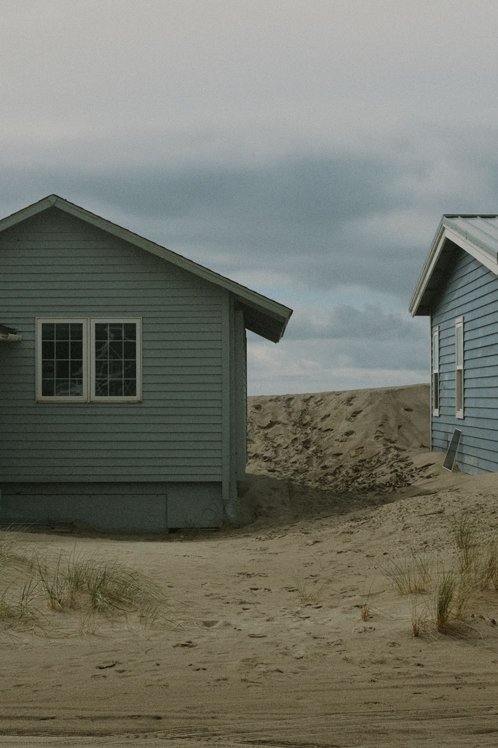 a couple of houses sitting on top of a sandy beach