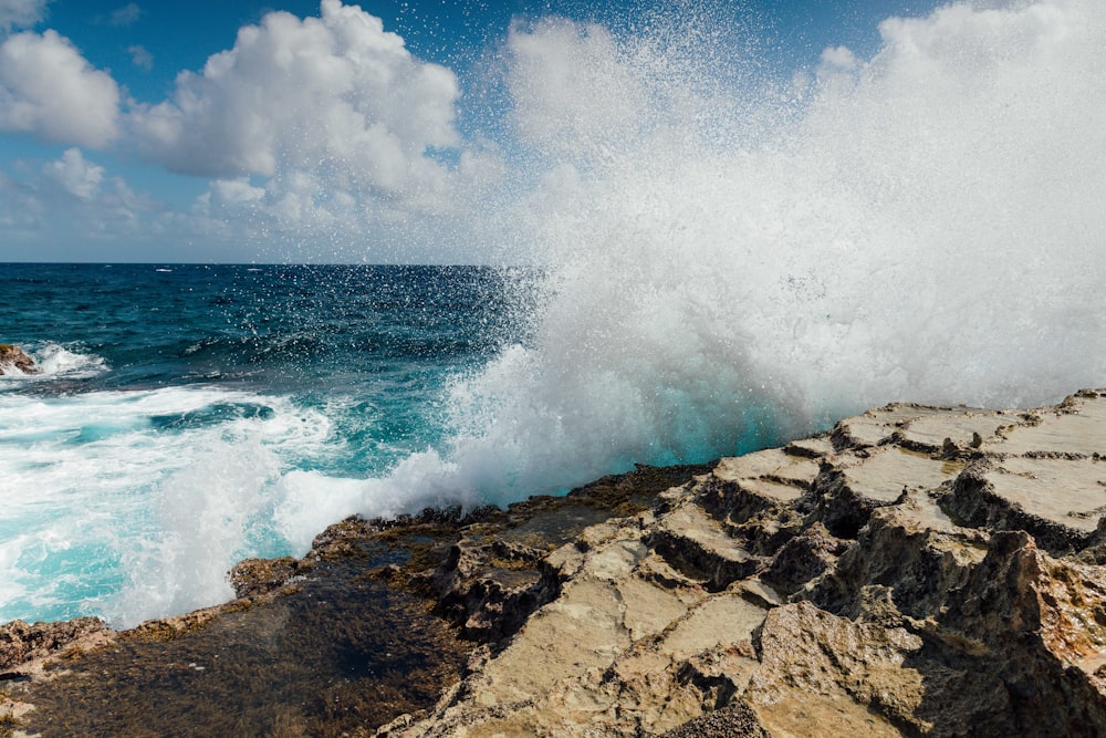 a large wave crashes into the rocks near the ocean