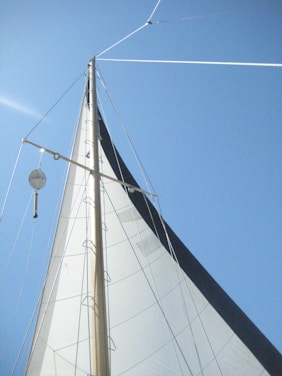 a white sail boat with a blue sky in the background