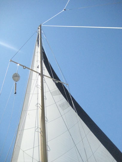a white sail boat with a blue sky in the background