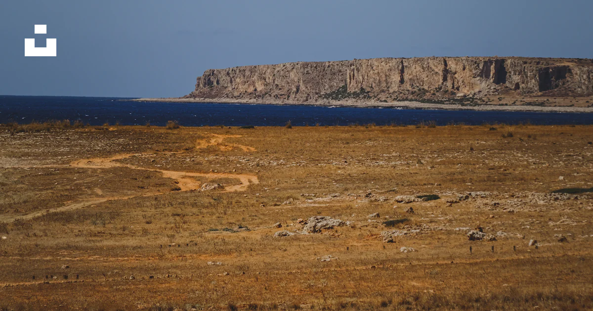A large open field with a rock outcropping in the distance photo – Free ...