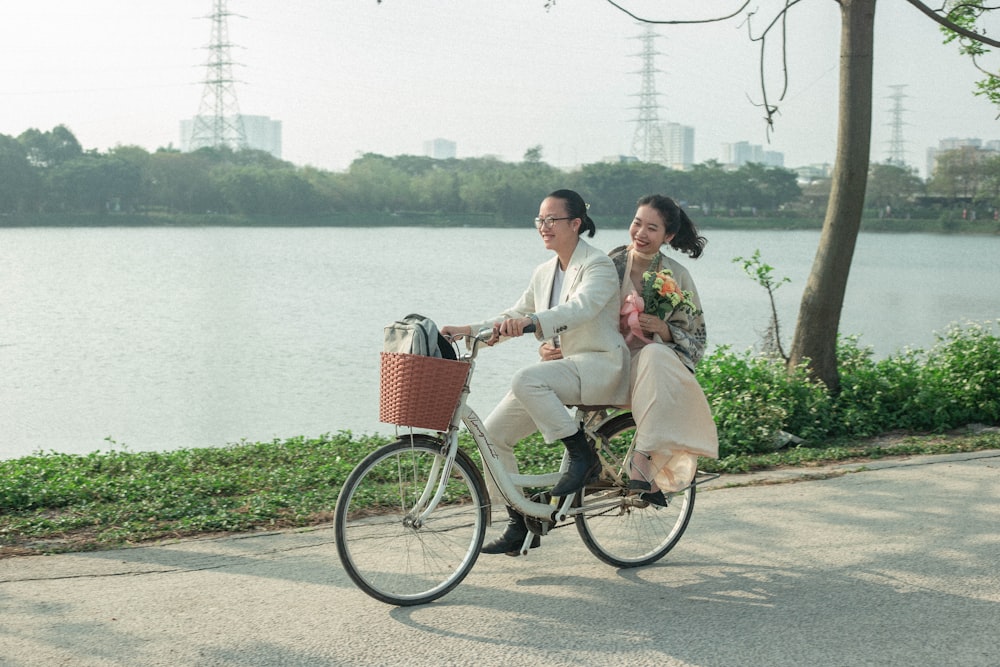 a man and woman riding a bike next to a lake