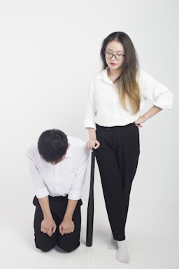 a man kneeling down next to a woman holding a tie