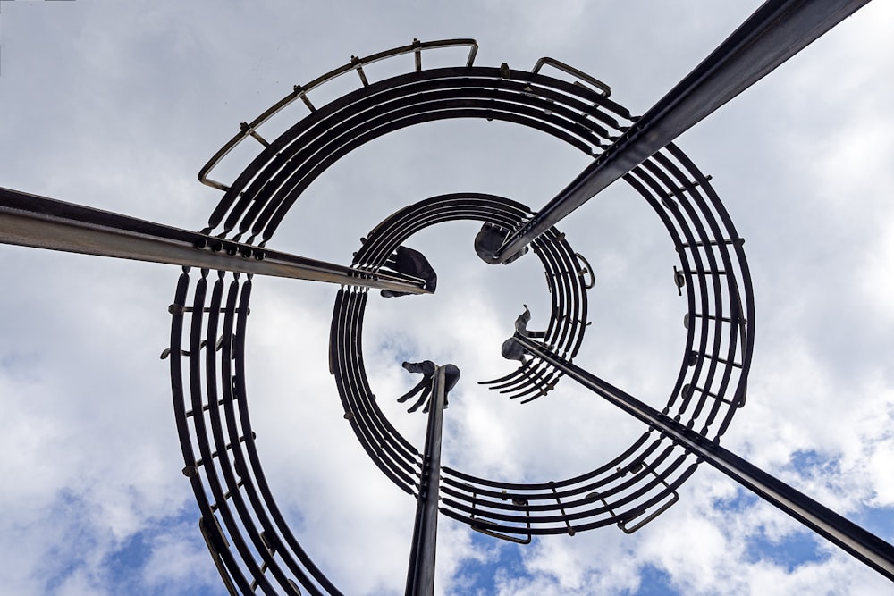 looking up at a metal sculpture with a sky background