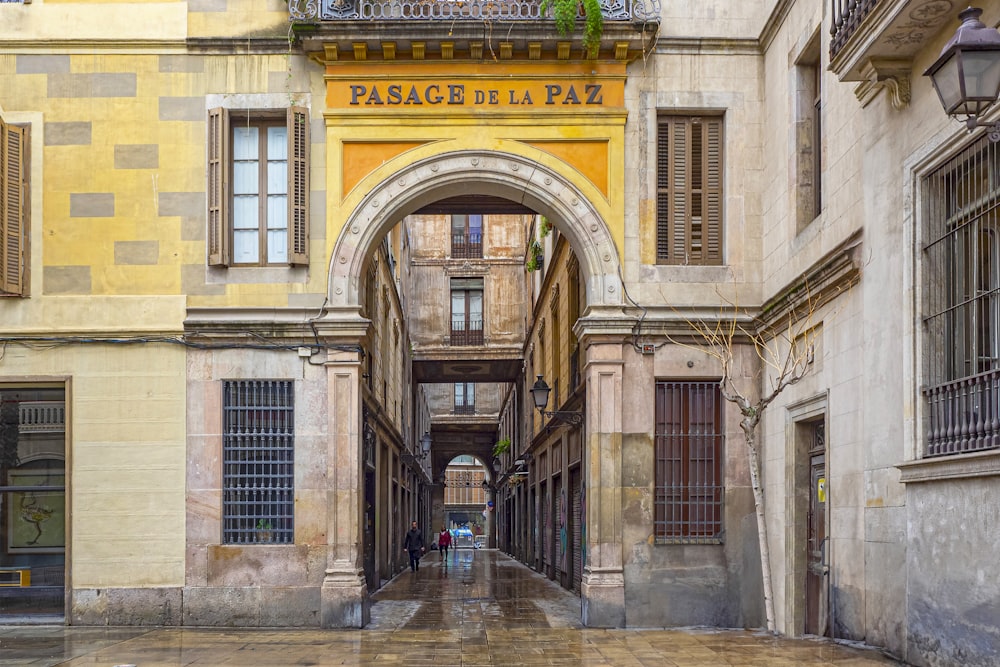 a narrow street with a yellow building and a person walking down it