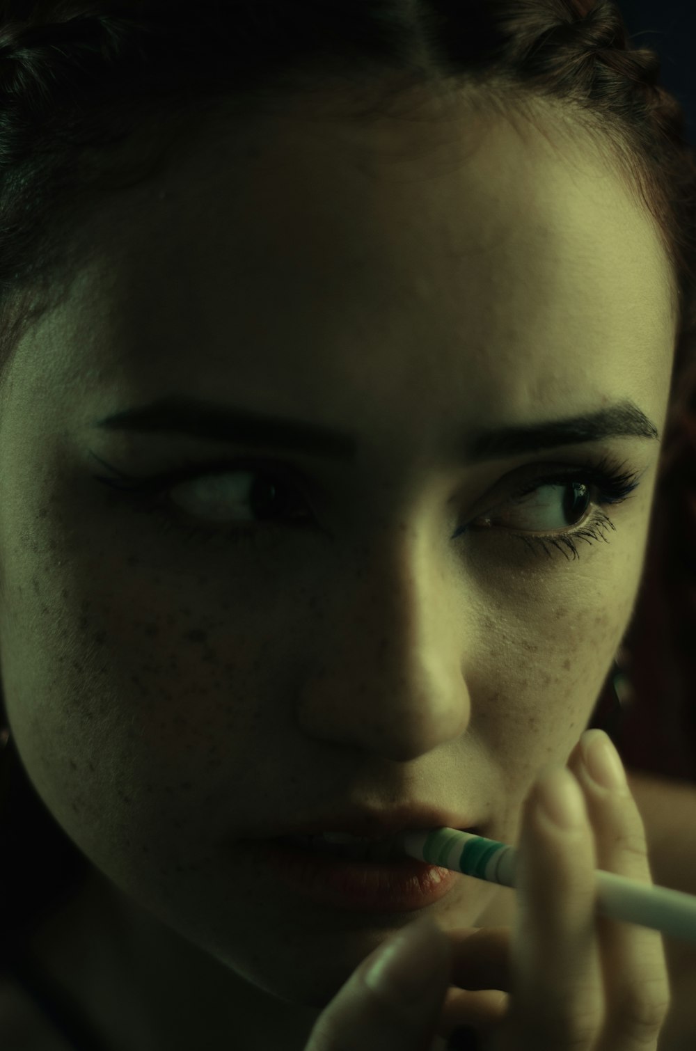 a woman with freckled hair is brushing her teeth