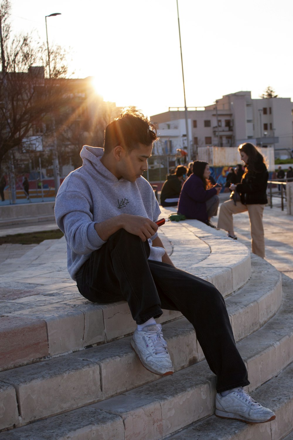 a man sitting on a stone step looking at his cell phone