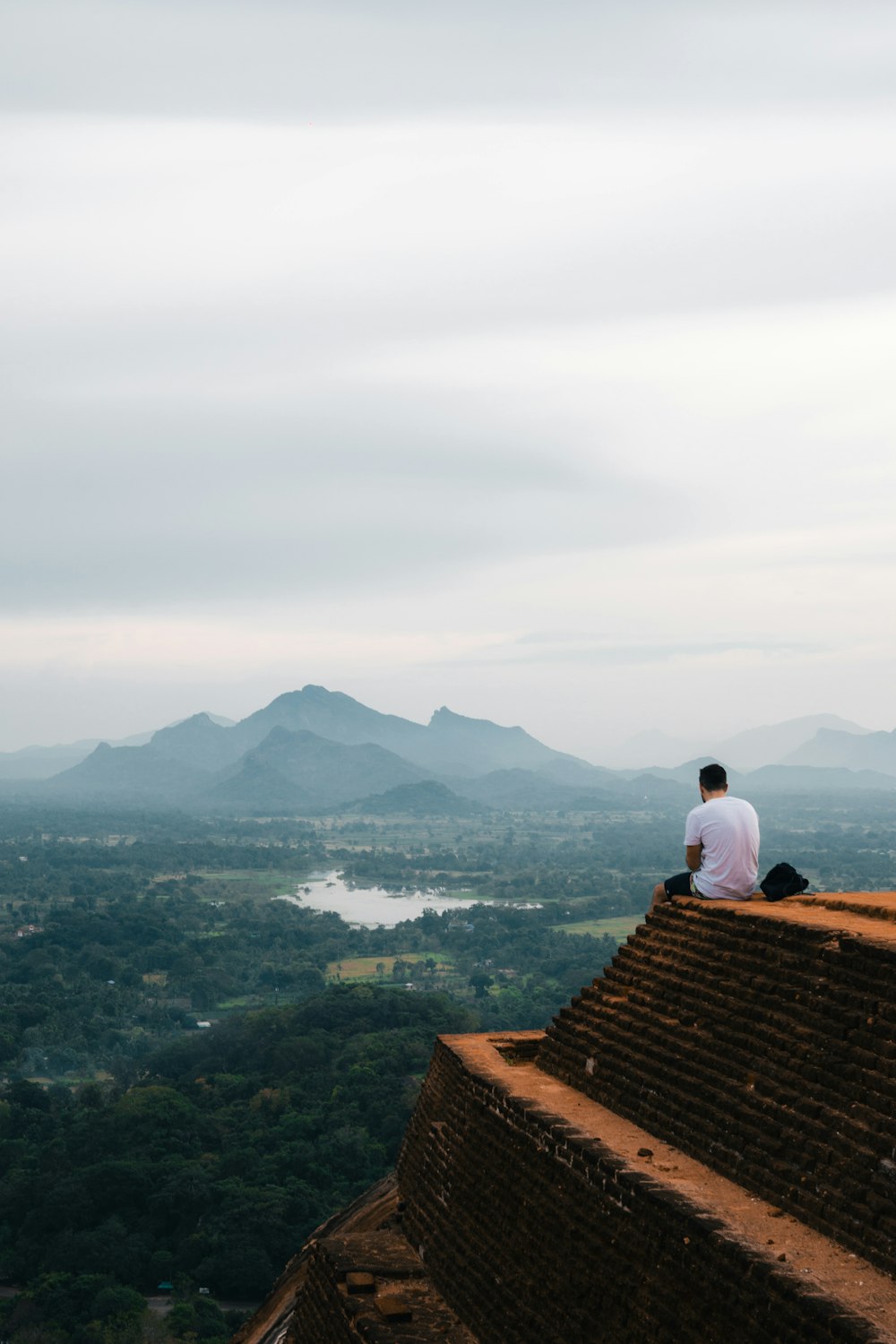 a man sitting on top of a roof next to a lake