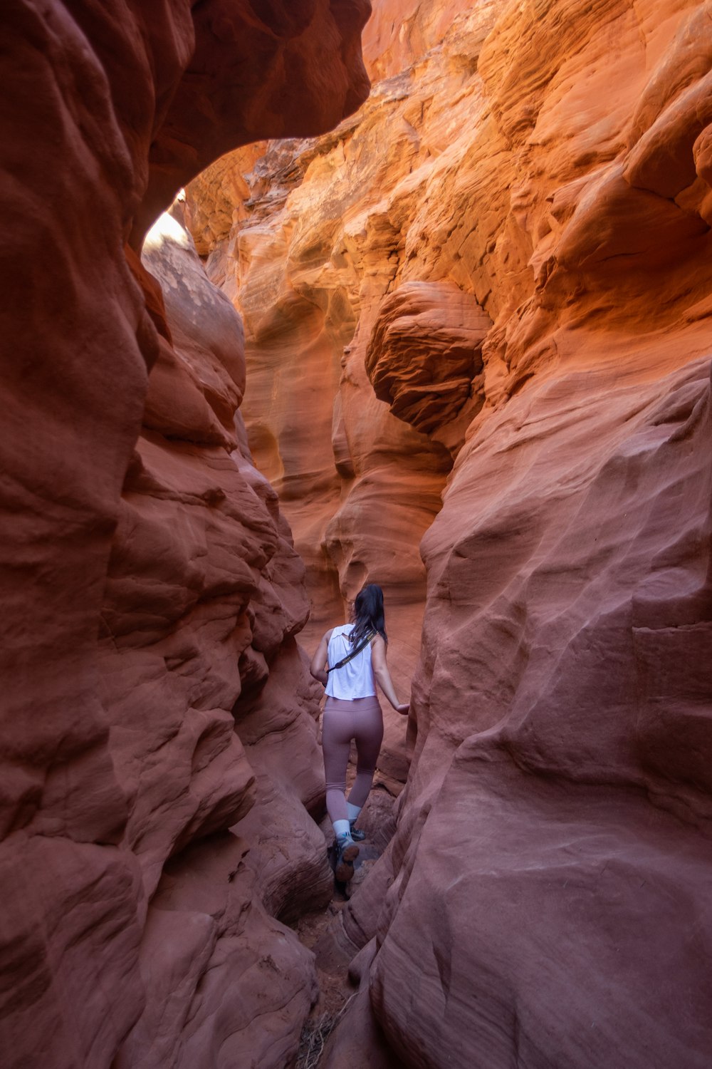 a woman hiking through a narrow slot in a canyon