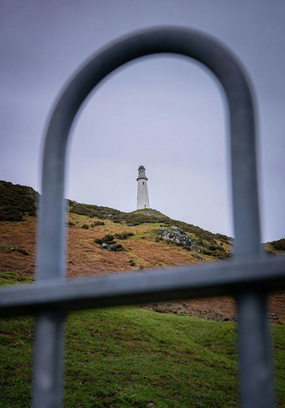 a view of a lighthouse through a metal fence