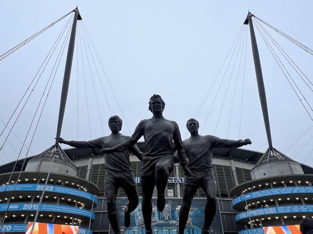 a statue of three men standing in front of a stadium