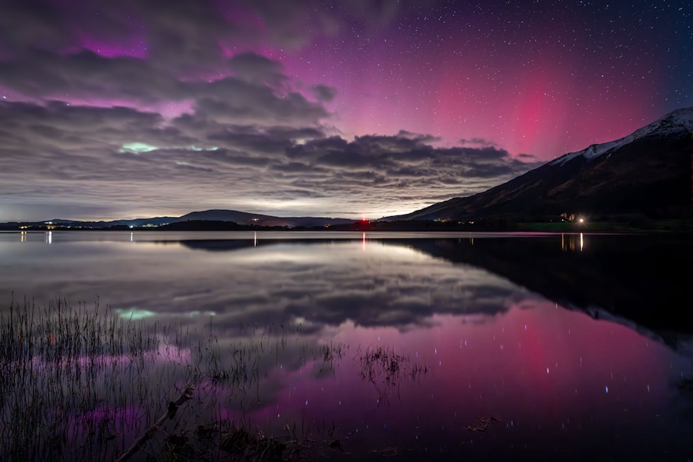 um lago com uma montanha no fundo sob um céu roxo