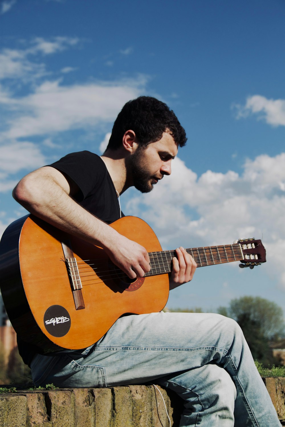 a man sitting on a wall playing a guitar