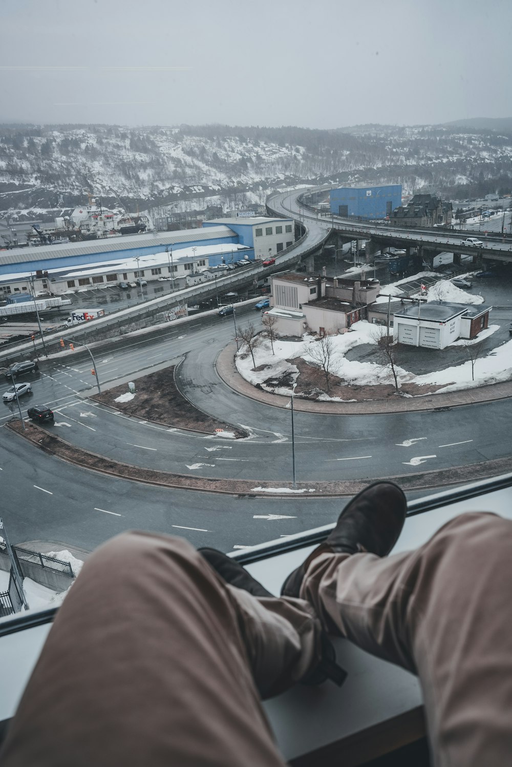 a person sitting on a window sill looking at a street